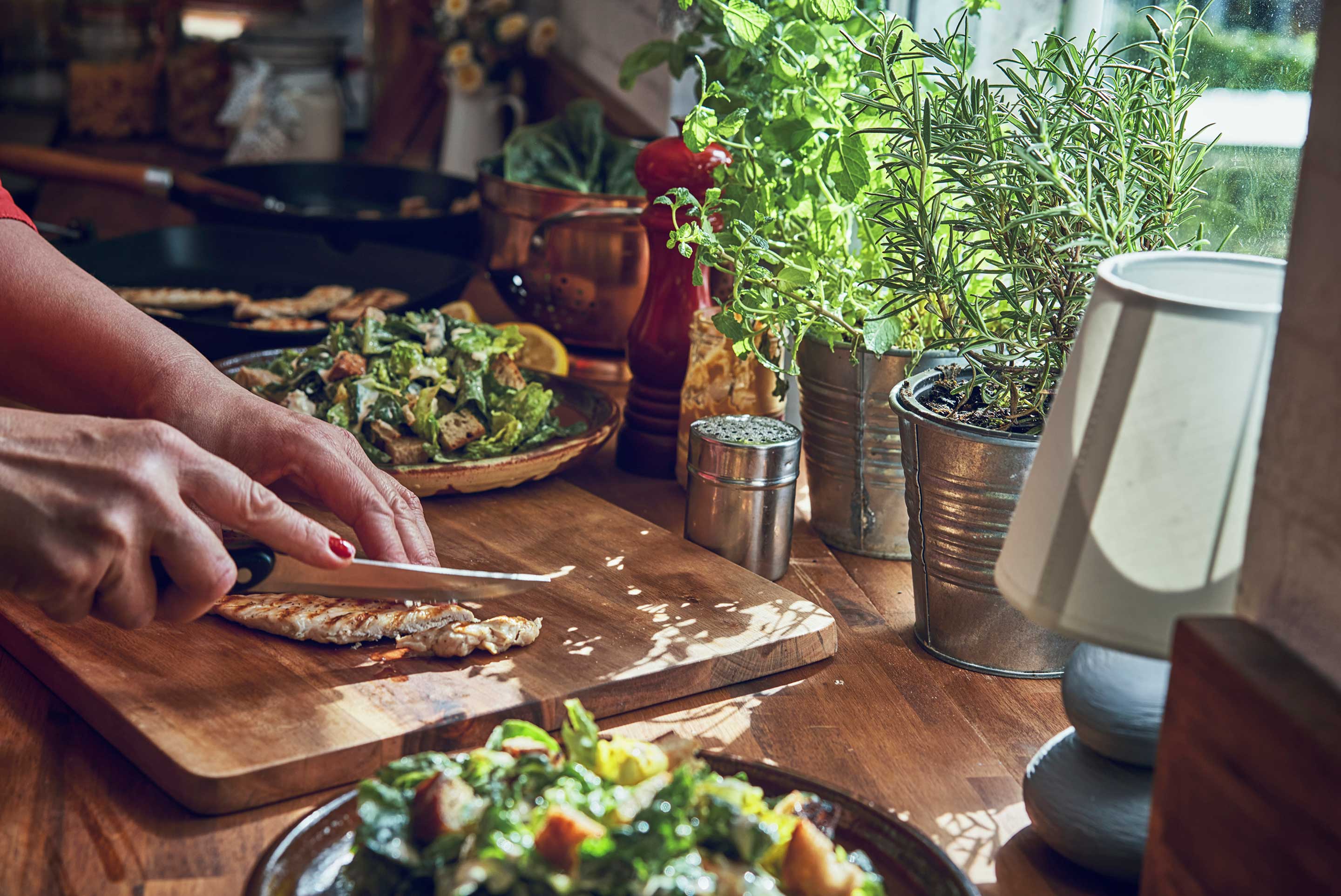 femme découpe du poulet sur une planche de bois