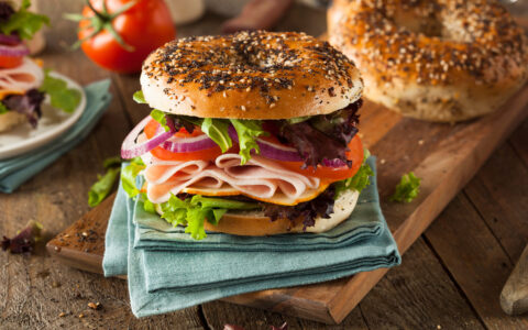 bagel sandwich au jambon et aux légumes posé sur une serviette bleu