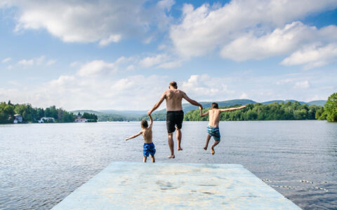 homme et enfants sautant dans un lac