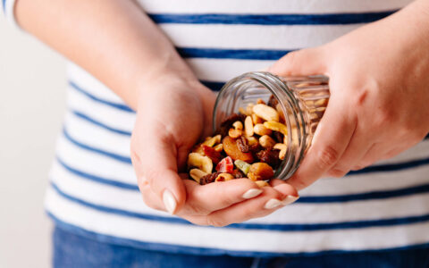 femme tenant un pot avec un mélange de fruits sec